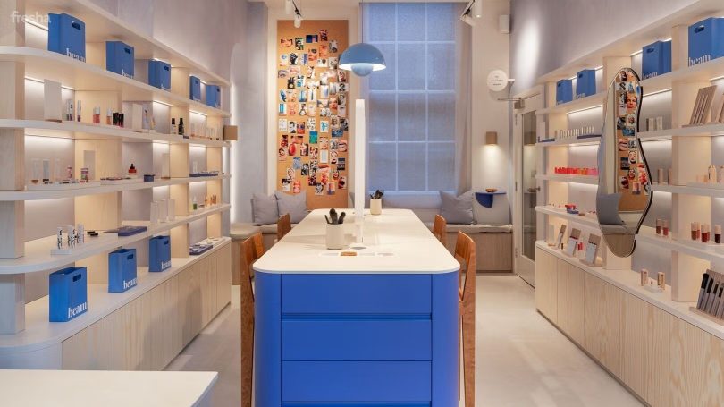 Modern shop interior with blue and white decor, shelves filled with products, and a central island.