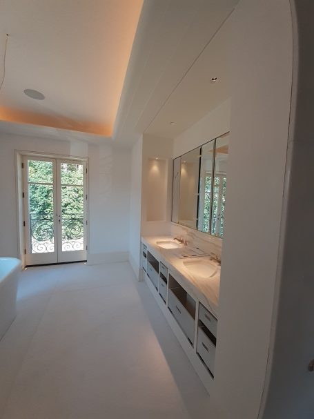 Spacious bathroom with dual sinks, large mirrors, and doors leading to an outdoor view.