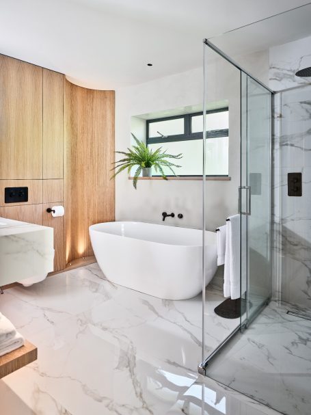 Modern bathroom featuring a freestanding tub, glass shower, and wooden accents.