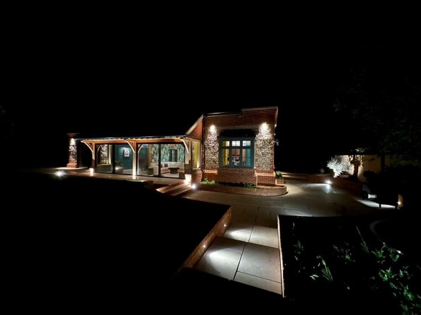 Modern house illuminated at night, featuring a welcoming porch and landscaped garden.